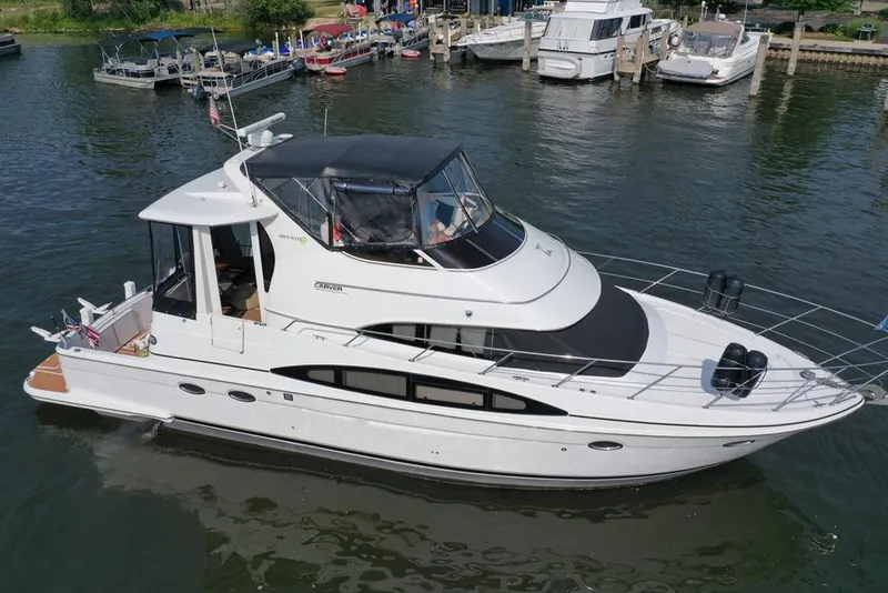 Slide: The Image of 2003 Carver 444 Cockpit Motor Yacht docked in a marina, surrounded by other boats. - 12