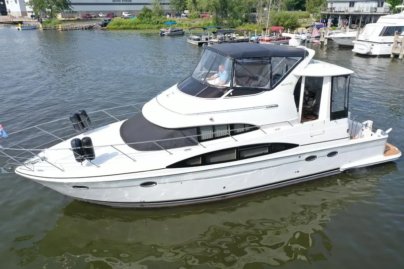 Slide: The Image of 2003 Carver 444 Cockpit Motor Yacht on calm water, docked at a marina. - 15