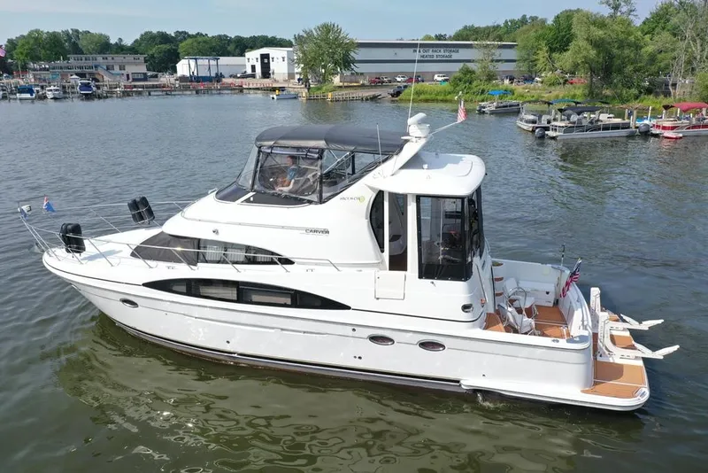 Slide: The Image of 2003 Carver 444 Cockpit Motor Yacht on a calm river, surrounded by docks and greenery. - 16