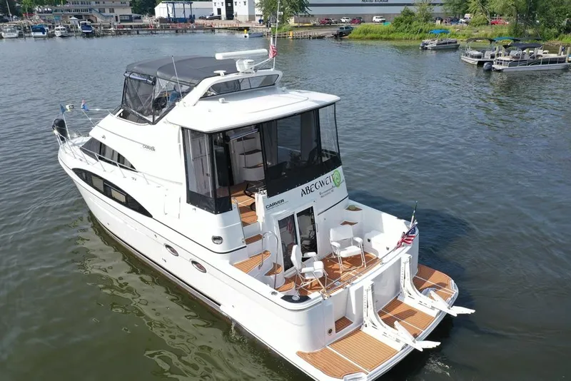 Slide: The Image of 2003 Carver 444 Cockpit Motor Yacht on water, featuring spacious deck and elegant design. - 18