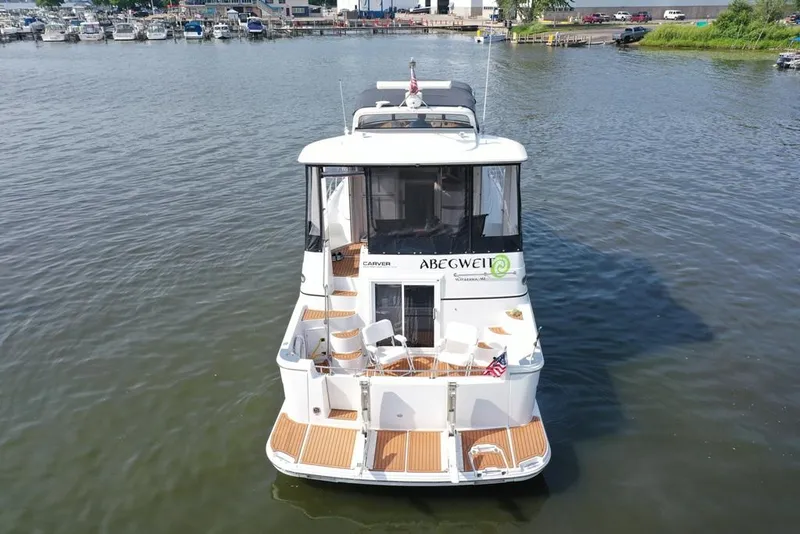 Slide: The Image of 2003 Carver 444 Cockpit Motor Yacht on calm water, rear view with docked boats in background. - 20