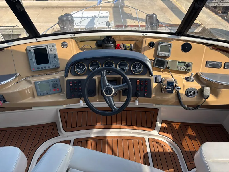 Slide: The Image of 2003 Carver 444 Cockpit Motor Yacht helm with navigation instruments and wood-accented controls. - 23
