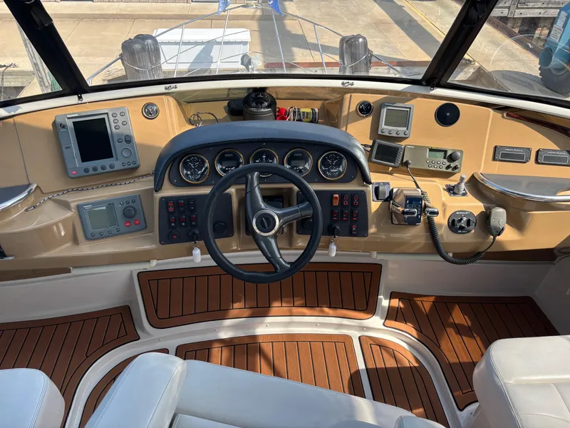 Slide: The Image of 2003 Carver 444 Cockpit Motor Yacht helm with navigation instruments and steering wheel. - 24