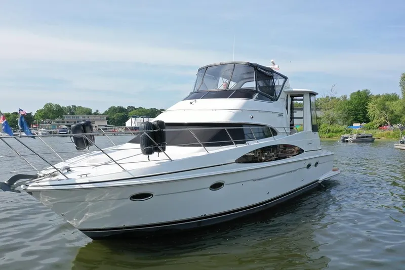 Slide: The Image of 2003 Carver 444 Cockpit Motor Yacht on a serene lake, surrounded by lush greenery. - 4