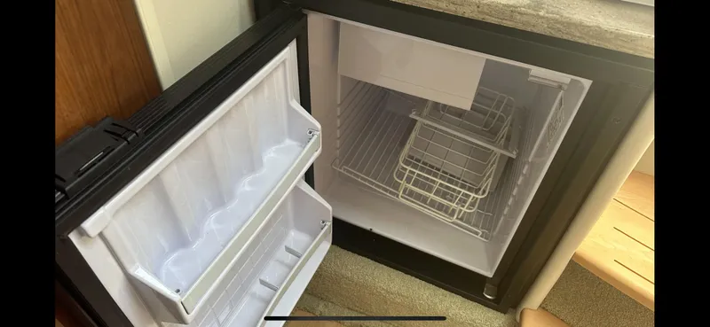 Slide: The Image of Open mini fridge in 2018 Formula 370 Super Sport boat, showing empty shelves and door storage. - 16