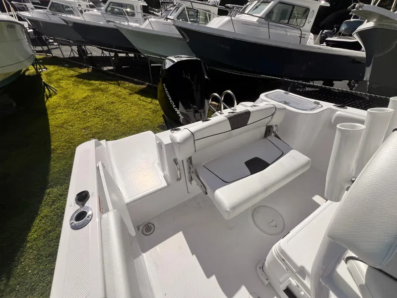 Slide: The Image of 2023 Wellcraft 222 Fisherman boat interior with seating and motor, displayed outdoors. - 5