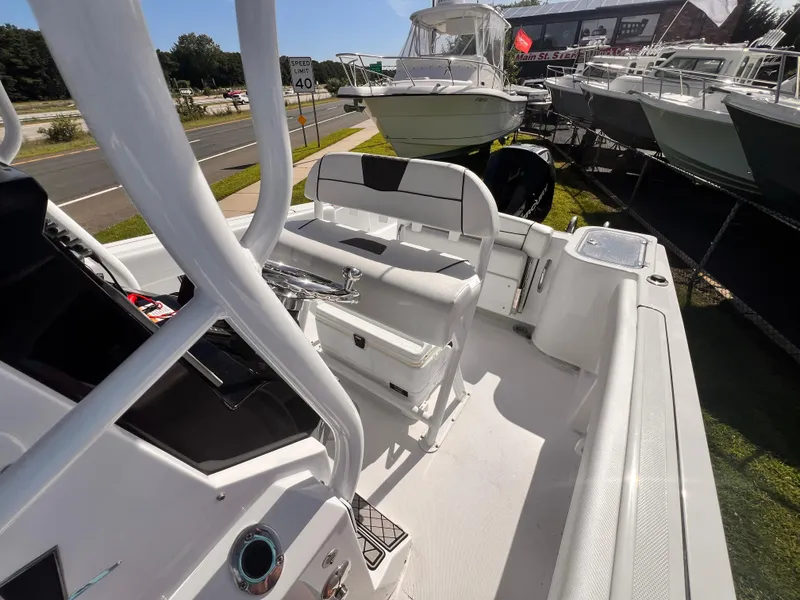 Slide: The Image of 2023 Wellcraft 222 Fisherman boat interior, showcasing seating and console, parked near a road. - 6
