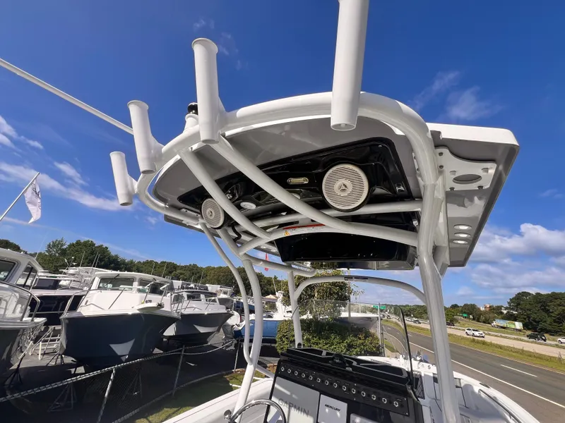 Slide: The Image of 2023 Wellcraft 222 Fisherman boat with T-top and rod holders, docked under a clear blue sky. - 8