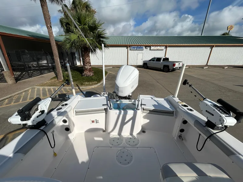Slide: The Image of 2013 Everglades 230 Dual Console boat interior with fishing equipment, parked near a palm tree. - 18