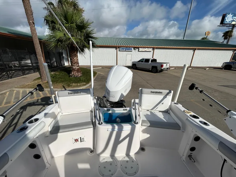 Slide: The Image of 2013 Everglades 230 Dual Console boat with outboard motor, parked near a building. - 19