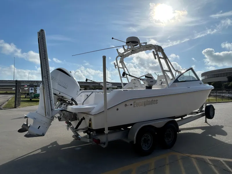 Slide: The Image of 2013 Everglades 230 Dual Console boat on trailer under sunny sky. - 5