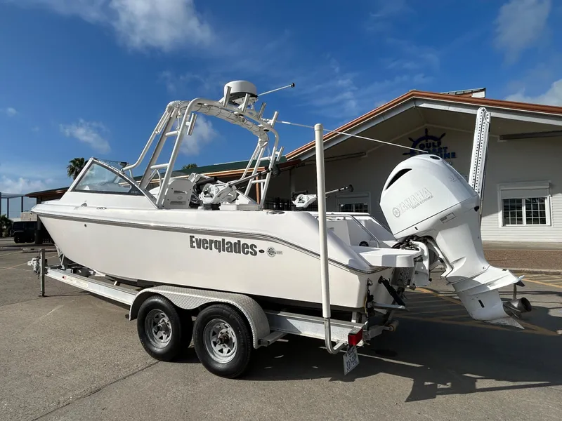 Slide: The Image of 2013 Everglades 230 Dual Console boat on trailer, parked outside a building under a clear sky. - 7