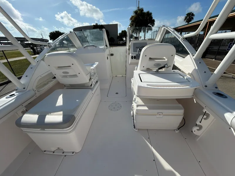 Slide: The Image of 2013 Everglades 230 Dual Console boat interior with seating and storage under a sunny sky. - 9