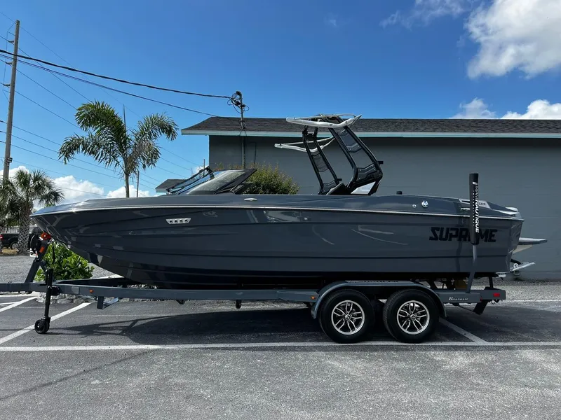 Slide: The Image of 2024 Supreme S220 boat on trailer, parked outdoors under clear blue sky. - 10