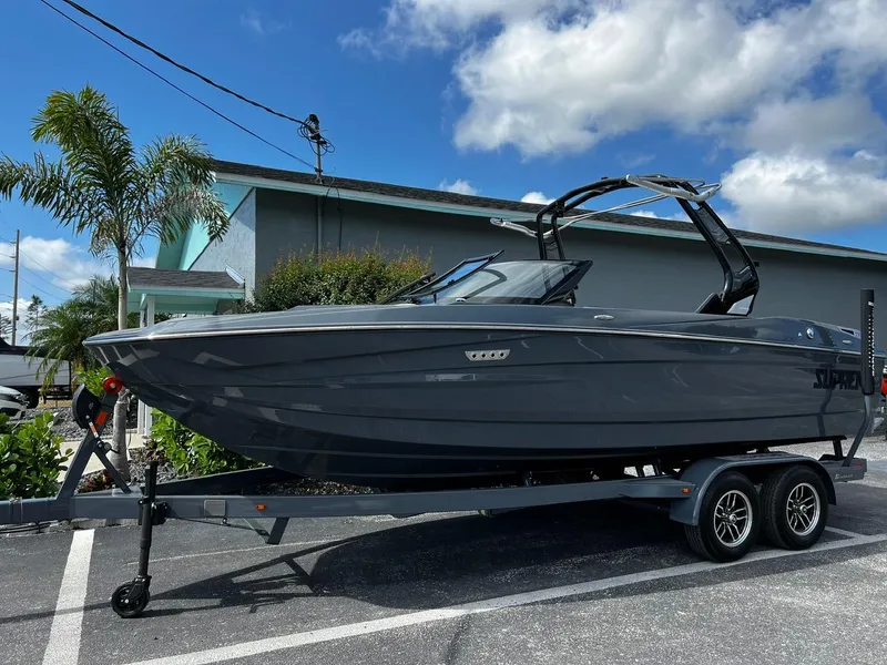 Slide: The Image of 2024 Supreme S220 boat on trailer, parked outdoors under blue sky. - 9