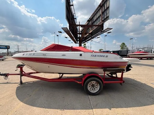Slide: The Image of 2002 Four Winns 190 Horizon boat on trailer, red cover, parked outdoors. - 1