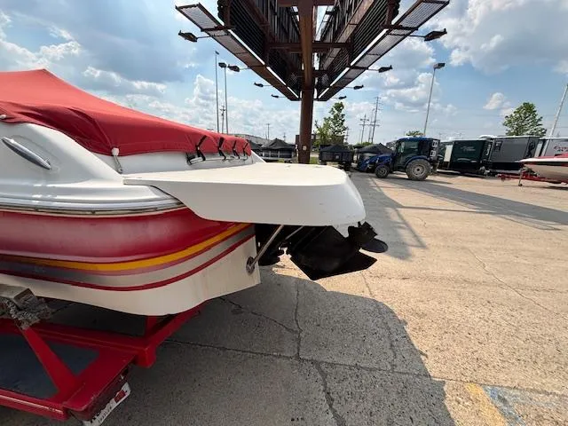 Slide: The Image of 2002 Four Winns 190 Horizon boat with red cover in a parking lot. - 2