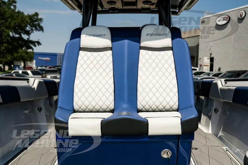 Slide: The Image of 2023 Statement 350 Open boat with blue and white seating, parked outdoors. - 36