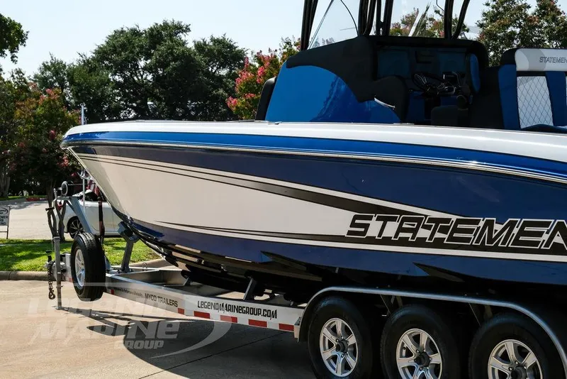 Slide: The Image of 2023 Statement 350 Open boat on trailer, blue and white design, parked outdoors. - 8