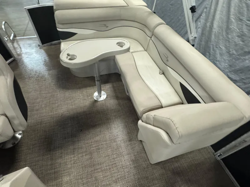 Slide: The Image of 2019 Bennington S21 boat interior with beige seating and a small table. - 11