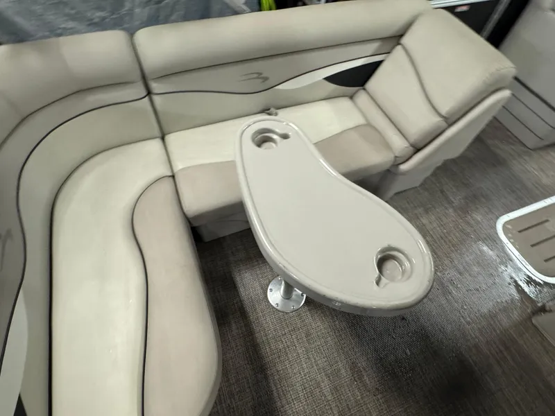 Slide: The Image of 2019 Bennington S21 boat interior with beige seating and oval table featuring cup holders. - 19