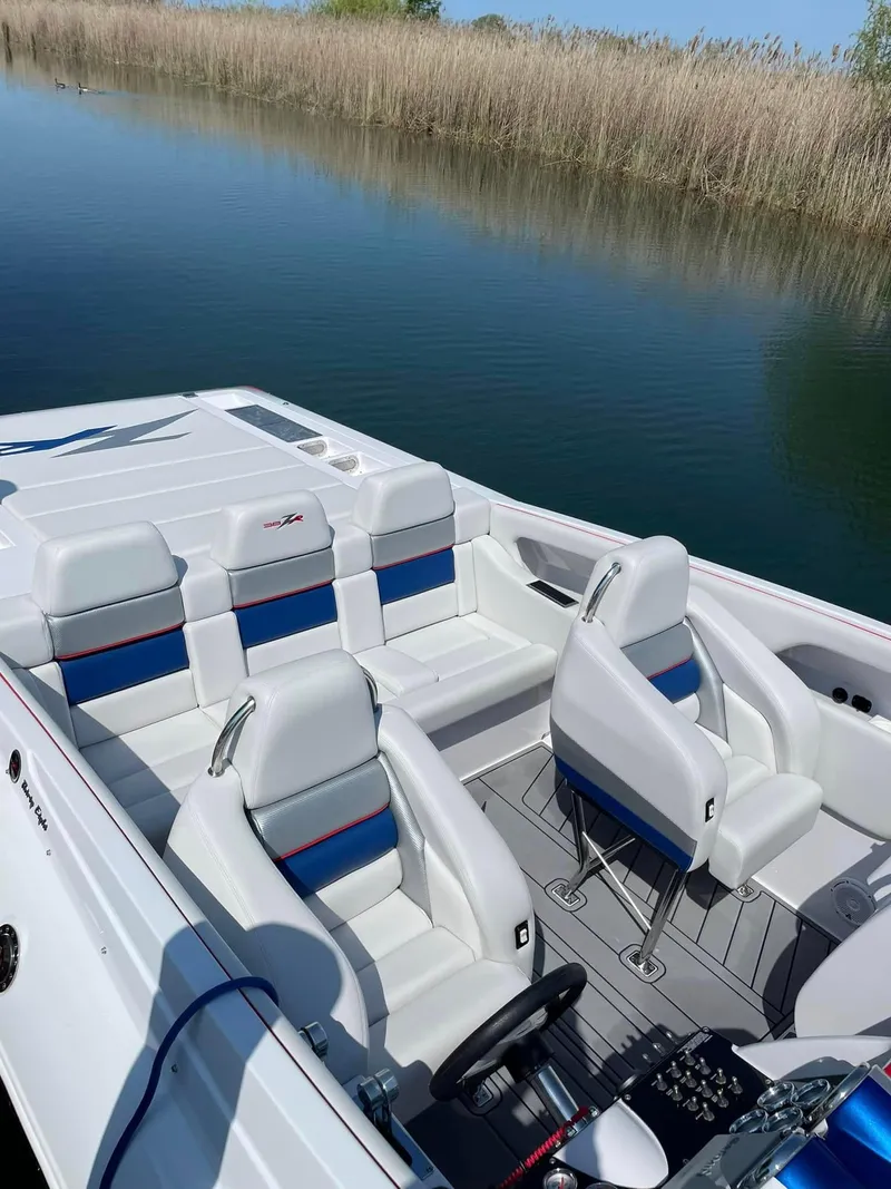 Slide: The Image of 2008 Donzi 38 ZR boat interior with white and blue seating, near calm water. - 10