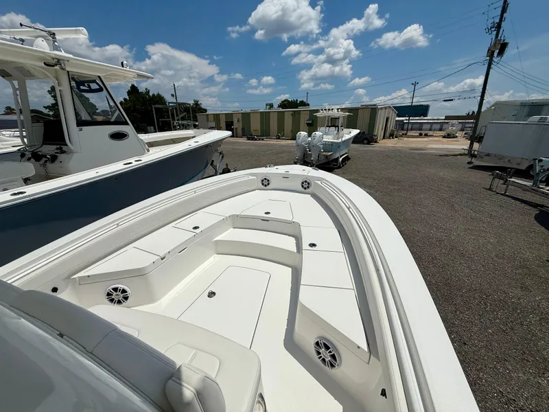 Slide: The Image of 2023 Regulator 26XO boat, white deck, parked outdoors under a blue sky. - 8