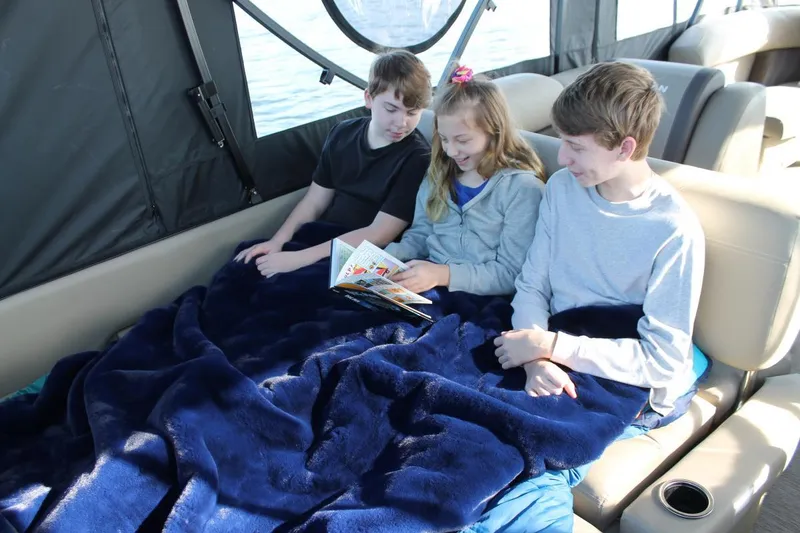 Slide: The Image of Manufacturer Provided Image: Children reading on a 2022 Sylvan Mirage 8522 Resorter boat, wrapped in blue blankets. - 13