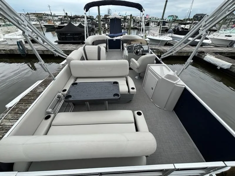 Slide: The Image of 2022 Sylvan Mirage 8522 Resorter pontoon boat interior at marina, featuring spacious seating and helm. - 8