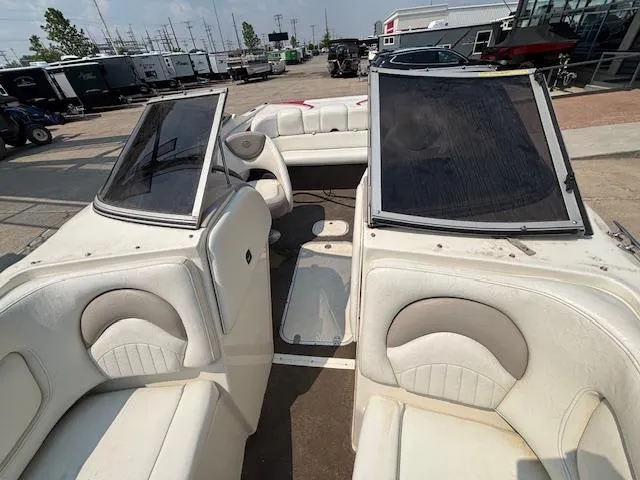 Slide: The Image of 2006 Stingray 220 LX boat interior with white seating and open windshield, parked outdoors. - 20