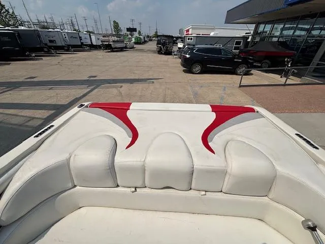 Slide: The Image of 2006 Stingray 220 LX boat interior with white and red seating, parked in a dealership lot. - 24