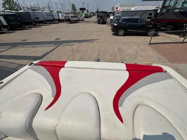 Slide: The Image of 2006 Stingray 220 LX boat interior with red and white seating, parked in a lot. - 26