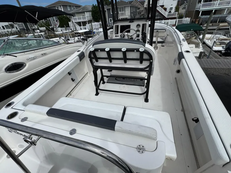 Slide: The Image of 2021 Robalo R222 Explorer boat interior with seating and console, docked at a marina. - 2