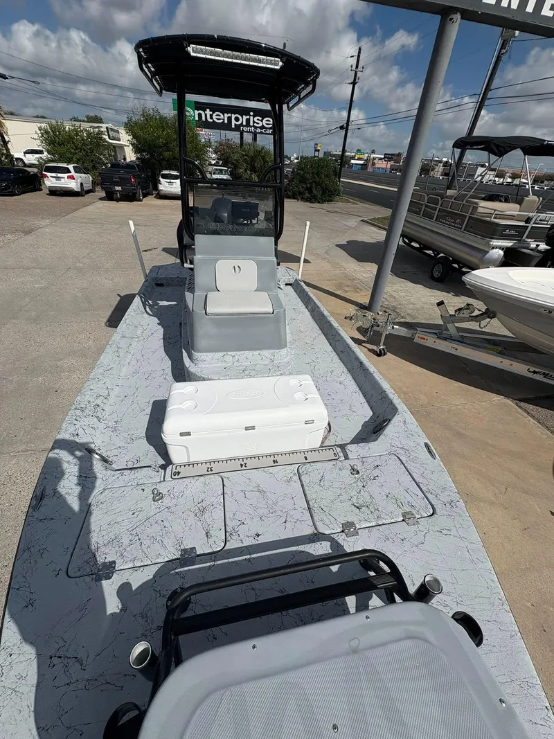 Slide: The Image of 2014 Shoalwater 21 Catamaran boat on display at dealership, featuring spacious deck and seating. - 10