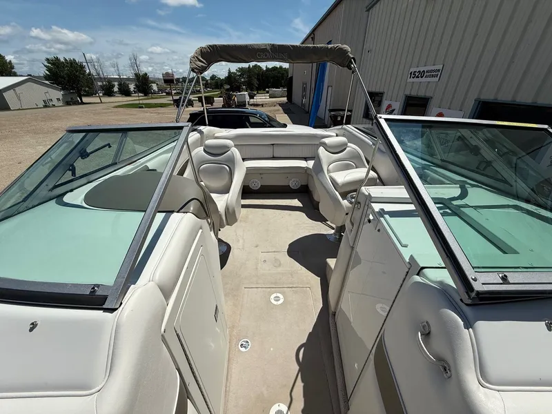 Slide: The Image of 2004 Crownline 266 BR boat interior with seating, windshield, and canopy in a sunny outdoor setting. - 10