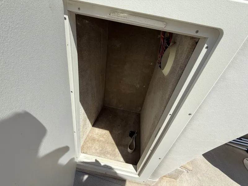 Slide: The Image of Storage compartment in a 2004 Crownline 266 BR boat, showing interior wiring and carpeted walls. - 12