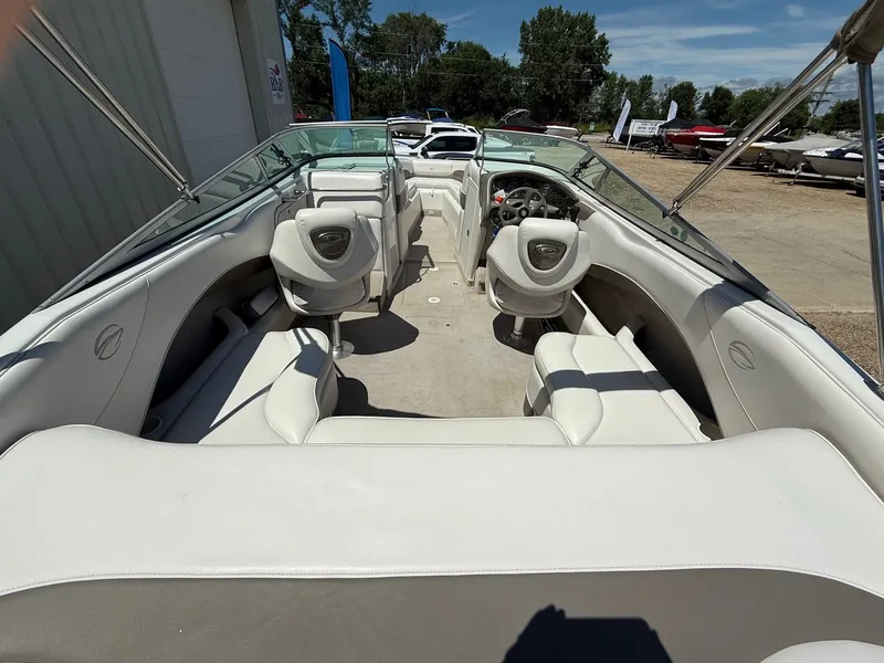 Slide: The Image of 2004 Crownline 266 BR boat interior with white seating and steering wheel, parked outdoors. - 7