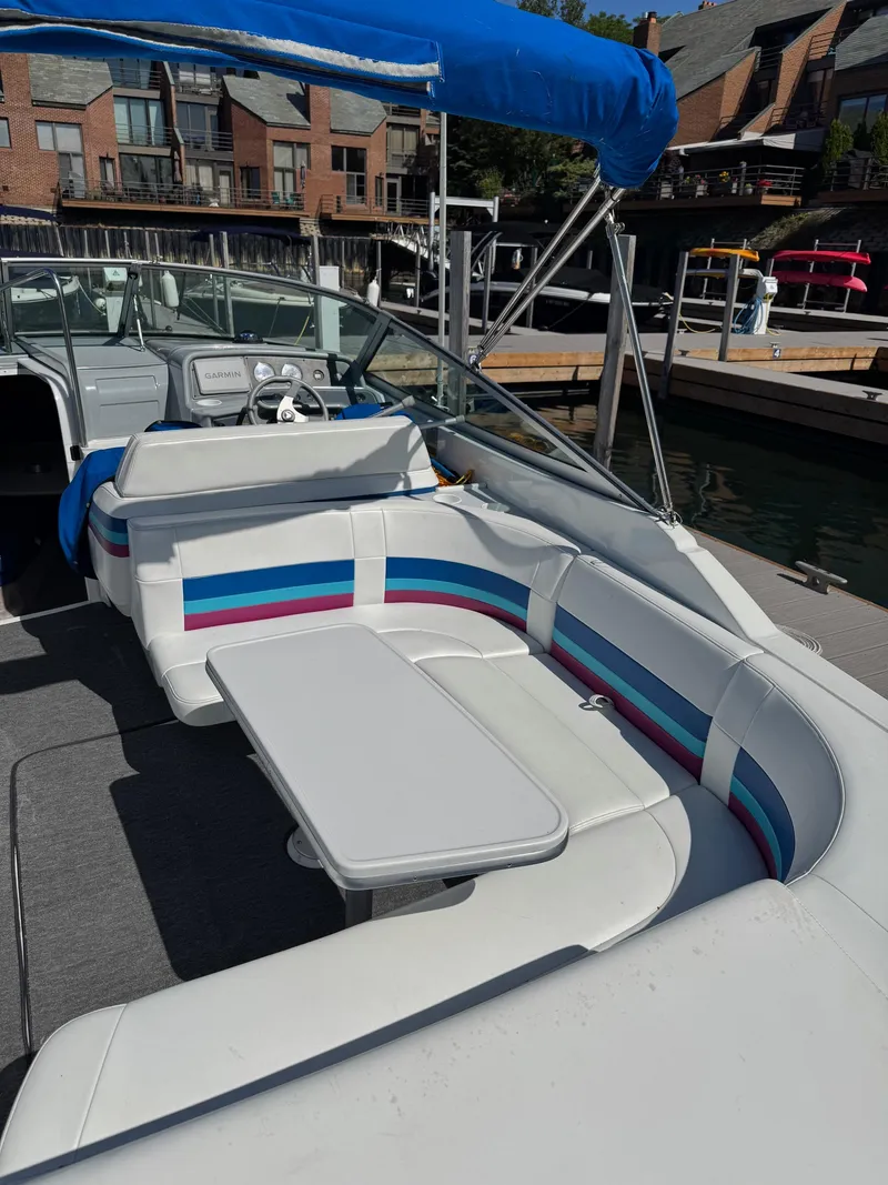 Slide: The Image of 1996 Formula 280 SS boat interior with white seating, colorful accents, and a table, docked at marina. - 10