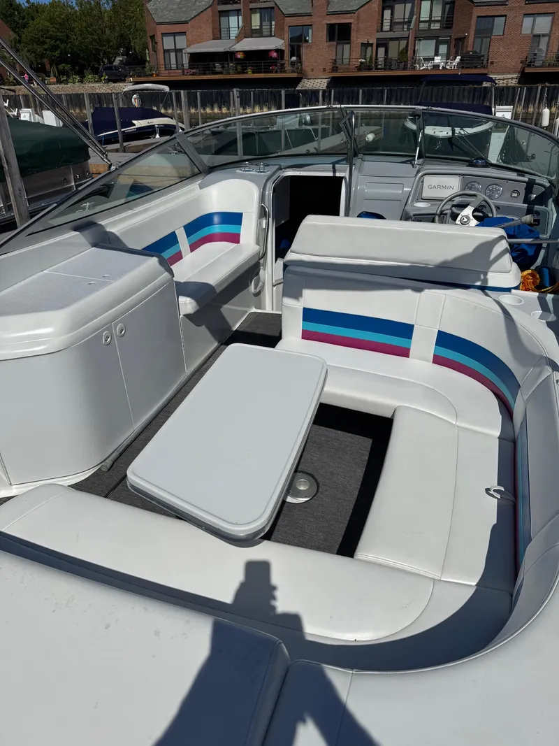 Slide: The Image of 1996 Formula 280 SS boat interior with white seating and colorful accents, docked near buildings. - 13