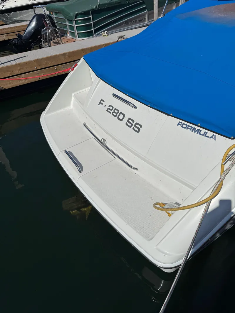 Slide: The Image of 1996 Formula 280 SS boat with blue cover docked at marina. - 2