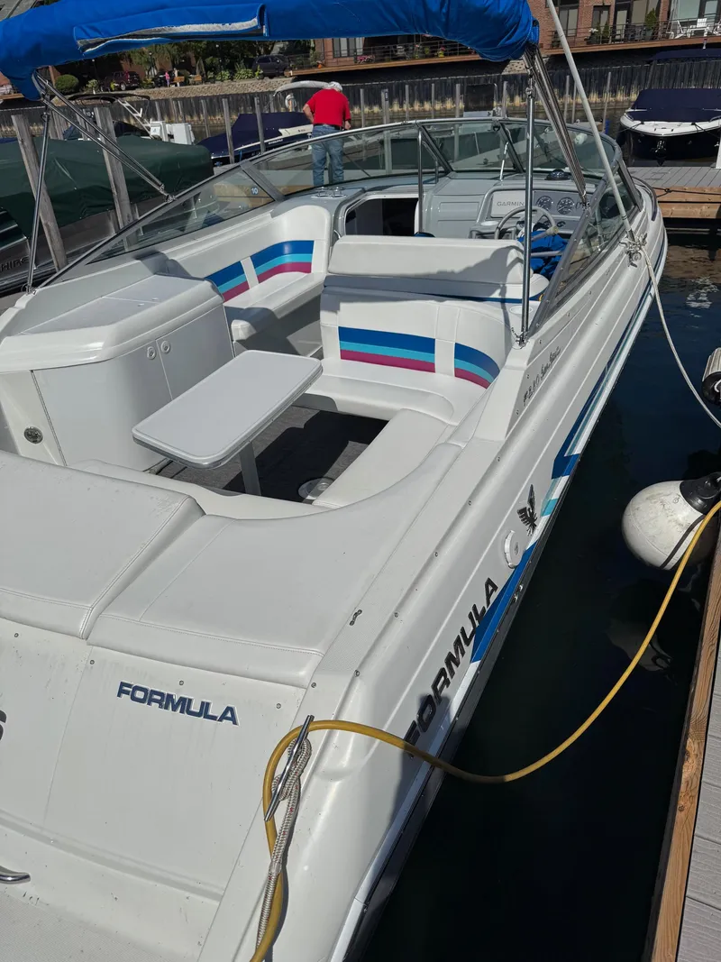 Slide: The Image of 1996 Formula 280 SS boat docked, featuring white seating with colorful stripes and a small table. - 20