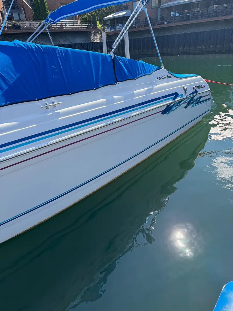 Slide: The Image of 1996 Formula 280 SS boat with blue cover docked on calm water. - 4