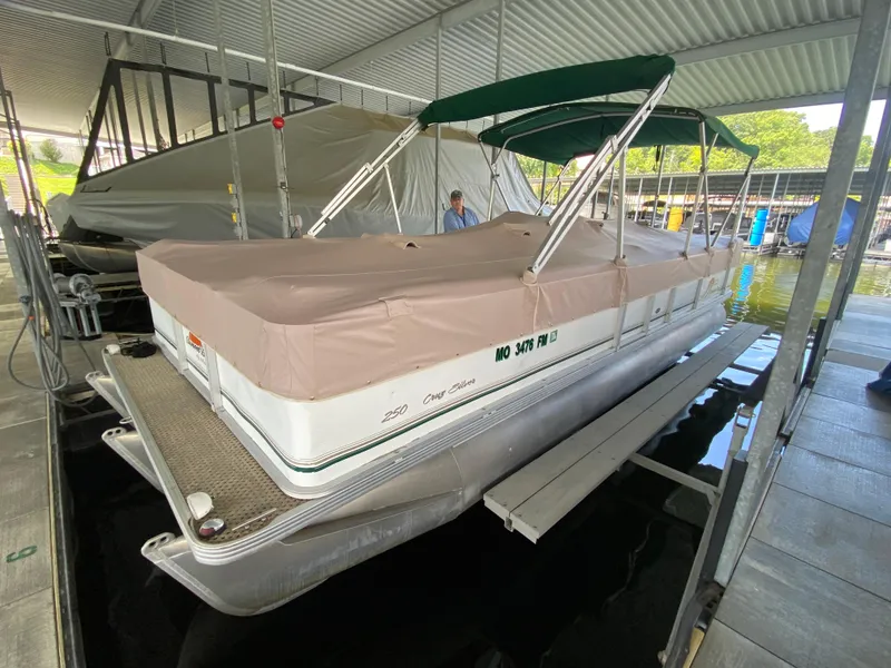 The Image of 2008 Sunset Bay Cruz 250 pontoon boat docked under a covered marina. - 0