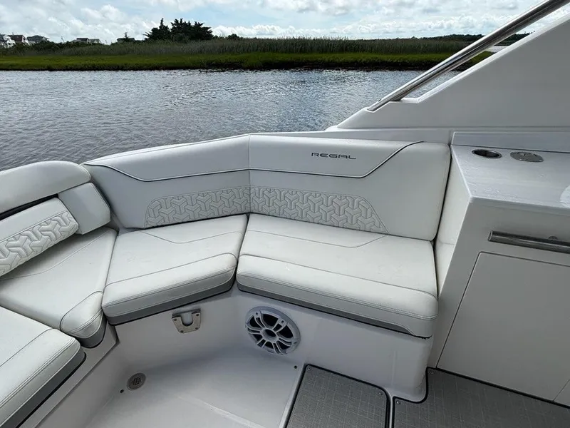 Slide: The Image of Luxurious seating on 2022 Regal LX36 boat, featuring elegant white upholstery and scenic water view. - 12