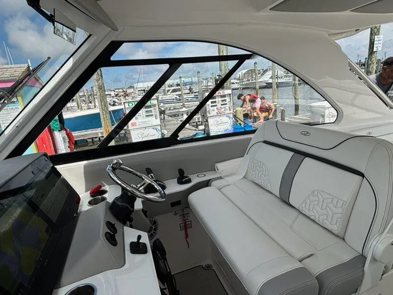 Slide: The Image of Interior of a 2022 Regal LX36 boat at a marina, featuring plush seating and steering controls. - 16