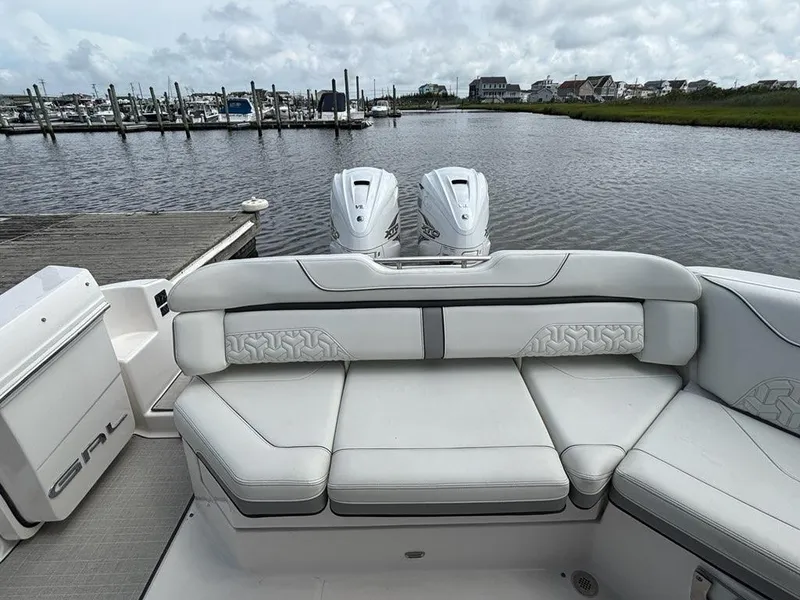 Slide: The Image of 2022 Regal LX36 boat with luxurious seating, docked by a marina under cloudy skies. - 19