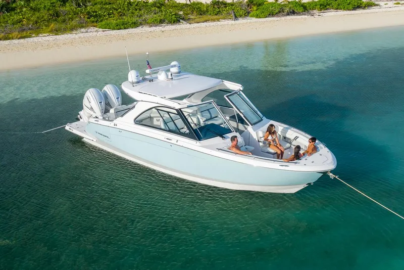 Slide: The Image of Manufacturer Provided Image: 2022 Regal LX36 boat anchored near a sandy beach with people relaxing onboard. - 23