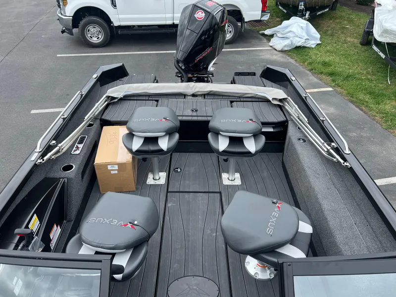 Slide: The Image of 2025 Vexus ADX 200 boat interior with seating and motor, parked outdoors. - 16