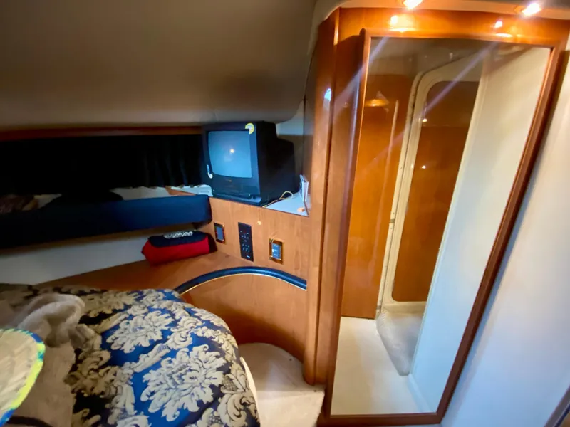 Slide: The Image of 1999 Sea Ray 400 Sundancer cabin interior with TV, bed, and wood paneling. - 22