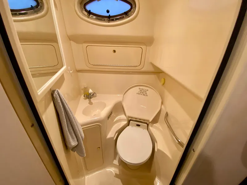 Slide: The Image of 1999 Sea Ray 400 Sundancer bathroom with toilet, sink, and porthole window. - 27